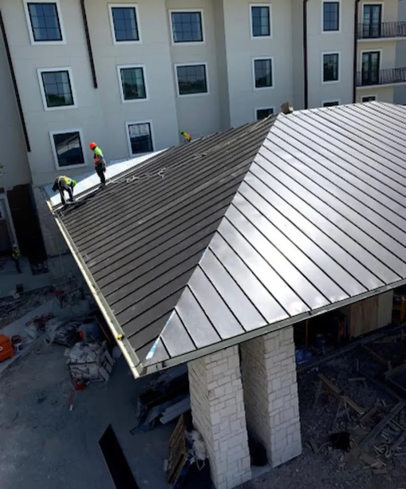 Crew installing standing seam metal roof panels on a commercial project in Southampton